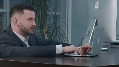 Man Typing on Laptop in Modern Office Setting
