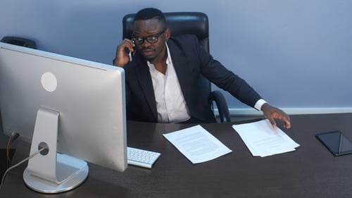 Businessman Talking on Phone at His Office Desk