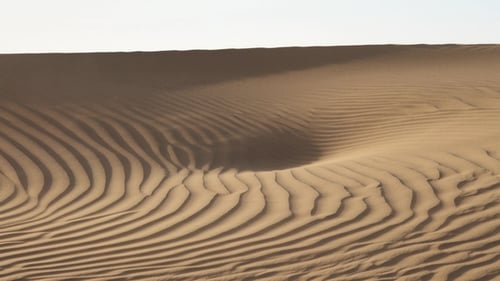 Sand weht im Wind über Dünen in der Sahara Wüste