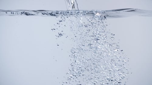 Wasser mit Luftblasen und Spritzern auf sauberem weißem Hintergrund gießen