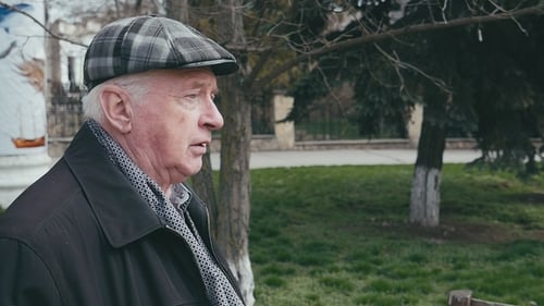 Brave Old Man Walking and Thinking in a Green Park Lane in Spring in