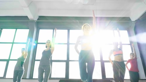 Women Exercise Together in Bright Fitness Studio
