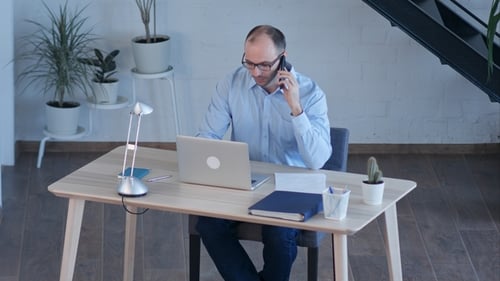 Man Working at Desk Talking on Phone