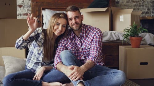 Portrait of Married Couple Sitting Together in New House, Holding Keys and Looking at Camera