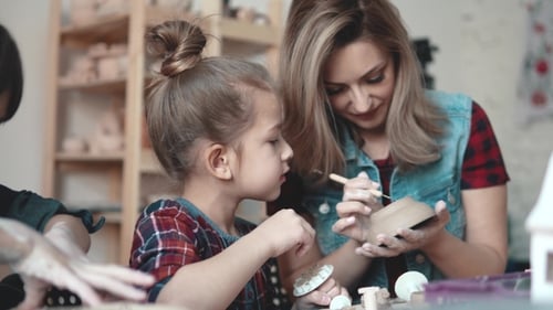 A Little Girl Is Making a Clay Craft in a Pottery Workshop. Mom and Child Spend Time Together Doing