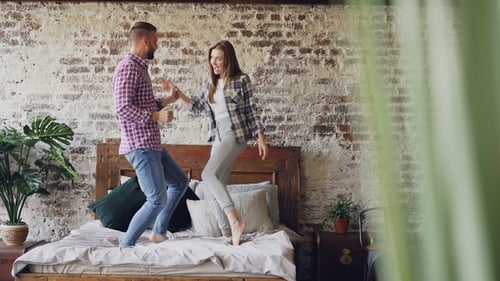 Couple Having Fun, Dancing on Bed Indoors