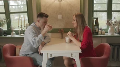 A Couple in Love is Sitting in a Cafe with Beautiful Decor Items at a Table with Drinks and