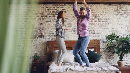 Couple Dancing on Bed Together in Bedroom