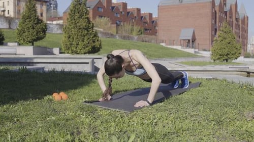 Woman Fitness Push-ups on the Grass in the Park