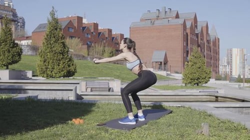 Young Woman Doing Squats in Urban Park