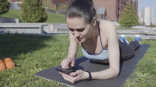 Woman Uses Phone While Exercising Outdoors