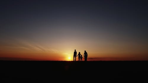 Silhouetted Family Holding Hands at Sunset