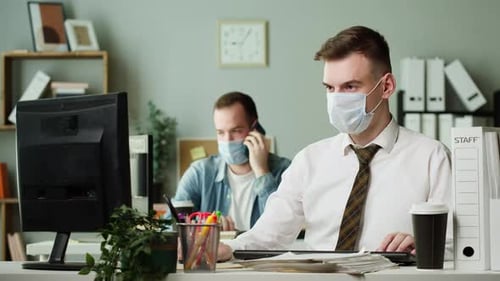 Travailleurs portant des masques de protection médicale travaillant dans les bureaux Employés assis à la table tapant à