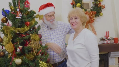 Senior Couple Embracing near Christmas Tree in Home