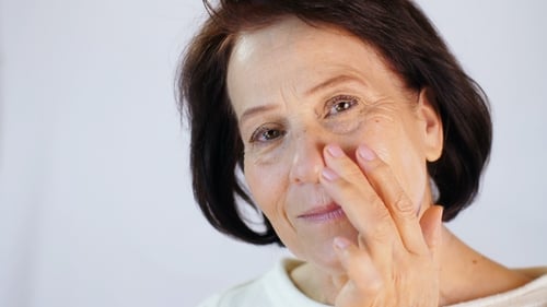 Senior Woman Applying Facial Cream for Skincare