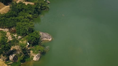 Green Water and Big Stones on Shore Beautiful Lake Aerial Shooting From Flying Drone. Road Along