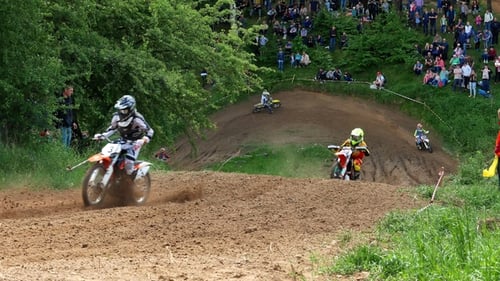 Motocross Riders Jumping Over Hilly Terrain Outdoors