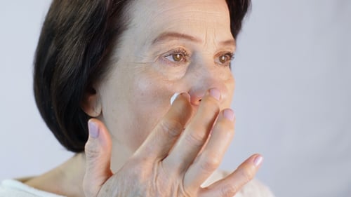 Senior Woman Applying Cream to Her Face