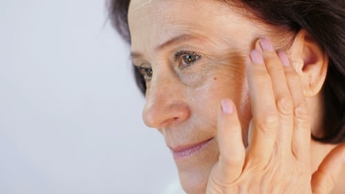 Woman Applying Cream to Face Close Up