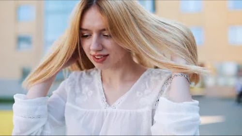 Le vent souffle sur les cheveux blonds d'une femme alors qu'elle se tient dehors