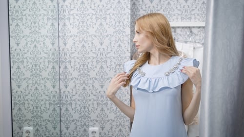 Woman in Blue Dress Adjusting Outfit in Fitting Room