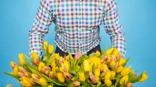 Smiling Man Holds Bouquet of Colorful Spring Tulips