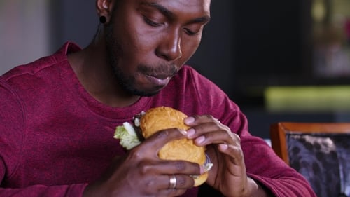 Happy Fat African American Man Eating a Hamburger.