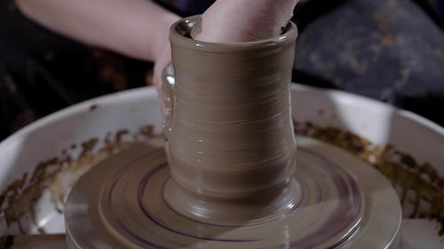Mains de potier talentueux façonnant la faïence et créant un chef-d'œuvre sur le tour de potier en