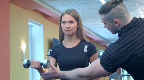 Woman with Her Personal Fitness Trainer in the Gym Exercising Power Gymnastics with Barbells
