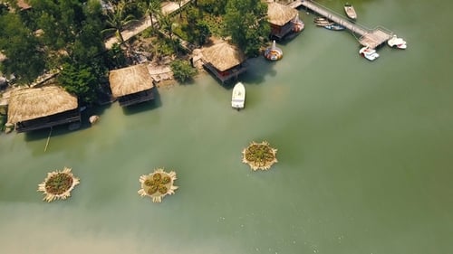 Summer Bungalows with Thatched Roof and Boat Pier on Shore Green Lake in Luxury Mountain Hotel