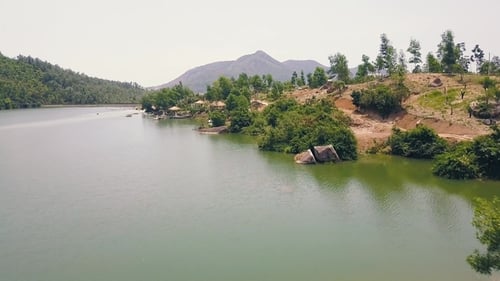 Exotic Bungalows with Thatched Roof and Boat Pier on Shore Mountain Lake in Luxury Hotel