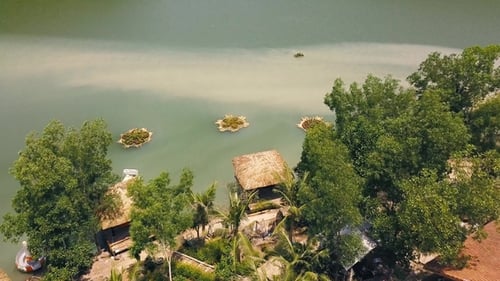 Tropical Bungalows with Thatched Roof and Boat Pier on Shore Green Lake in Resort Hotel Mountain