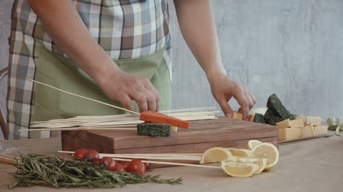 Person Making Cheese and Tomato Skewers