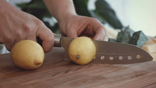 Female Hands Cutting Fresh Lemons on Cutting Board