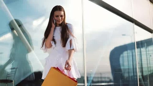 Sale, Consumerism: Young Woman with Smartphones and Shopping Bags Standing and Talking Near Shopping