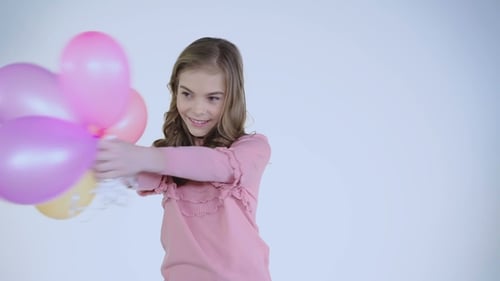 Happy Carefree Girl Plays with Balloons at Camera on Background