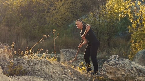 Der brutale Mann schlägt den Stein mit Hammer auf dem Felsen