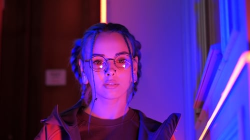 Young Pretty Girl with Unusual Hairstyle Near Glowing Neon Lights of the City at Night. Dyed Blue
