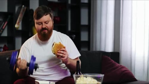 Bearded Man Working Out While Eating Hamburger