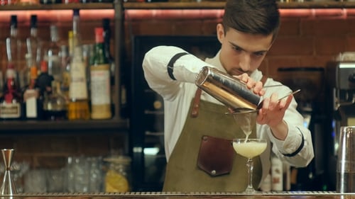 Young Bartender Makes Cocktail at a Bar