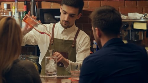 Barman Serving Glasses with Cocktails To the Couple Sitting at the Bar Counter