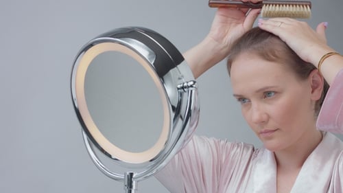 Woman Brushing Hair in Front of Mirror at Home