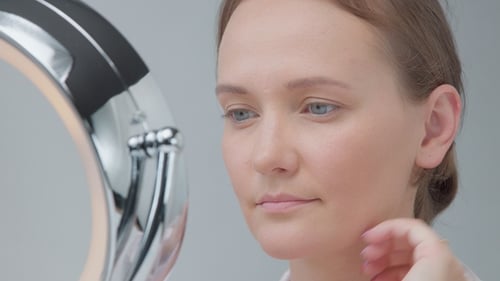 Woman Admiring Her Makeup in a Round Mirror