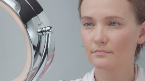 Woman Applying Makeup in Mirror Close Up
