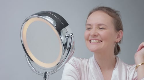 Woman Inspecting Face in Illuminated Vanity Mirror