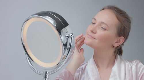 Woman Inspecting Face With Lighted Makeup Mirror