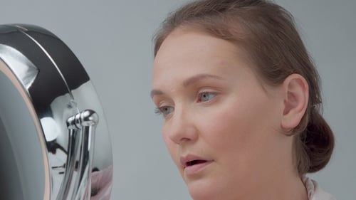 Caucasian Woman with Mirror with Ring Light with No Makeup Look Examine Her Skin and Makes Facial