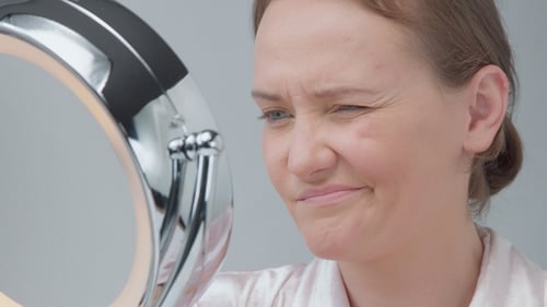 Woman Examining Her Face in Mirror