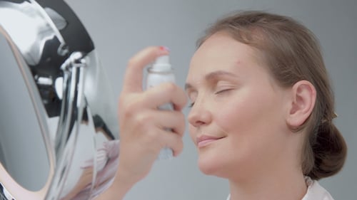 Woman Sprays Her Face With Water Mister