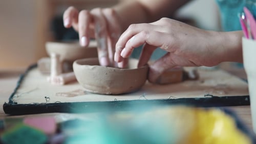 Hands Crafting Clay Bowl in Pottery Studio